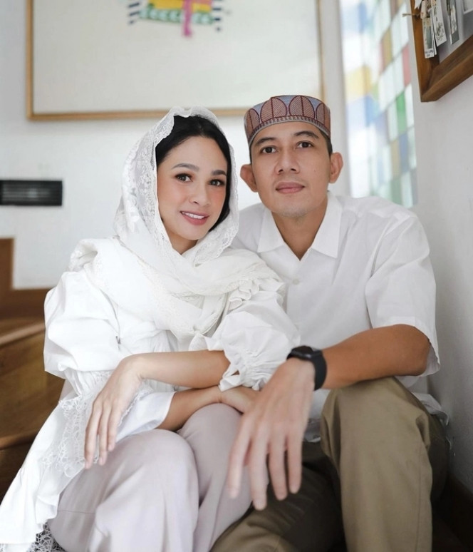 Andien Aisyah dan sang suami memilih busana serba putih saat merayakan Idul Adha 2021. Andien mengenakan blouse putih dengan lengan balon, sementara sang suami tampil mengenakan kemeja putih dan kopiah